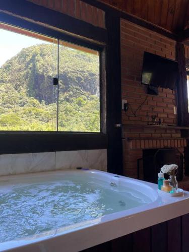a bathroom with a large tub with a window at Chalé Floresta Mauá in Resende