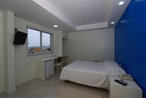 Schlafzimmer mit einem Bett, einem Schreibtisch und einem Fenster in der Unterkunft Hotel Don Zepe in Florianópolis