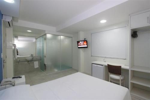 a bedroom with a white bed and a sink and a shower at Hotel Don Zepe in Florianópolis