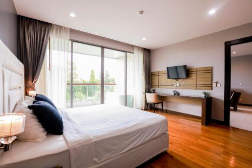 una camera da letto con un letto e una grande finestra di The Regent Bangtao Apartments gorgeous view of the jungle a Bang Tao Beach