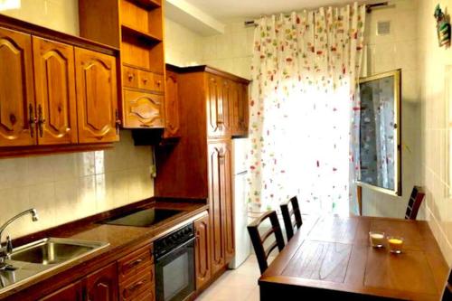 une cuisine avec des placards en bois et une table en bois avec des chaises dans l'établissement Casa playa Las Canteras, à Las Palmas de Gran Canaria