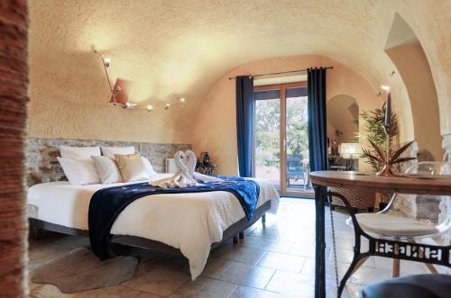 a bedroom with a bed in a room with a table at Le Mas Lauralie in Méjannes-lès-Alès