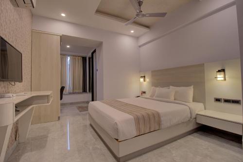 um quarto com uma cama, um lavatório e uma televisão em Greenstones Boutique Hotel em Nashik