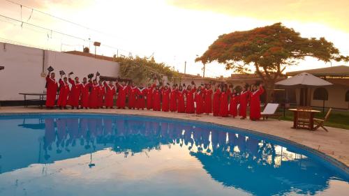 a group of people in red robes standing next to a pool at Hospedaje El Cascabel in Sunampe