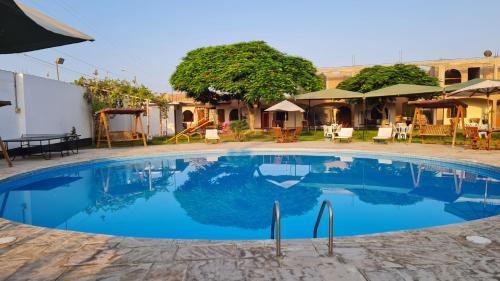 a large blue swimming pool with tables and chairs at Hospedaje El Cascabel in Sunampe