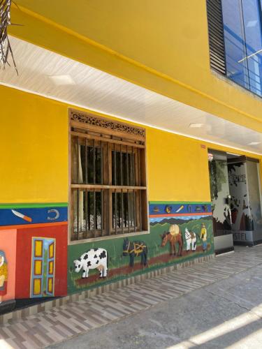 a yellow building with animals painted on the side of it at Oak Tree house in Guatapé