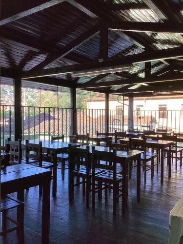 un restaurante con mesas y sillas de madera y ventanas en Pouso dos Viajantes Unidade Centro OuroPreto en Ouro Preto