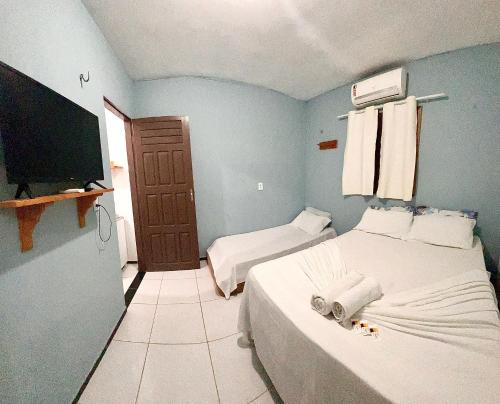 a bedroom with two beds and a flat screen tv at Pousada Apart Amor de Jeri in Jericoacoara