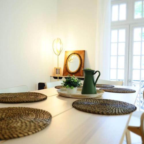 - une table à manger avec un miroir et un pichet vert dans l'établissement MAISON FAURE - Centre ville - Jardin - Garage, à Vichy