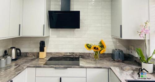 ケンブリッジにある3 Bedroom House Garden Free Parking 15 min to centre 5 min to motorwayの白いキャビネットと花瓶が並ぶカウンター付きのキッチン