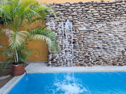 a waterfall in a stone wall next to a swimming pool at Hotel Victoria Queen Villavieja in Villavieja