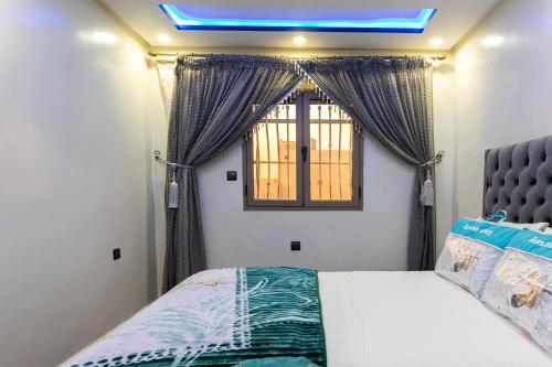 een slaapkamer met een bed en een raam met gordijnen bij ADAM APPARTEMENTS in Dakhla