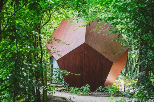 a building obscured by trees in front at Utopia Village - Art & Nature Lodges in Jurbise