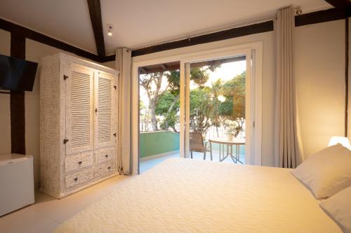 a bedroom with a bed and a sliding glass door at Porto Pacuíba Hotel in Ilhabela