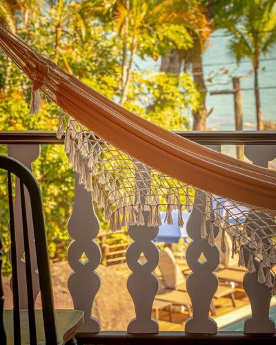 a hammock on a balcony with a table at Porto Pacuíba Hotel in Ilhabela