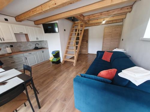 a living room with a blue couch and a kitchen at Smerekowa Ostoja in Smerek