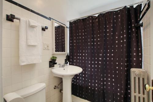 a bathroom with a sink and a shower curtain at Ideal, Spacious & Furnished 1BR Apartment - Cullom C2 in Chicago