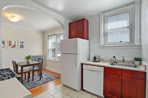 a kitchen with a white refrigerator and a table at Ideal, Spacious & Furnished 1BR Apartment - Cullom C2 in Chicago