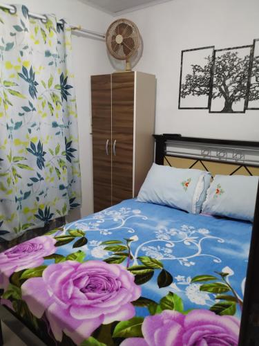 ein Schlafzimmer mit einem Bett mit lila Rosen in der Unterkunft Kitnet Praia de Ubatuba in São Francisco do Sul