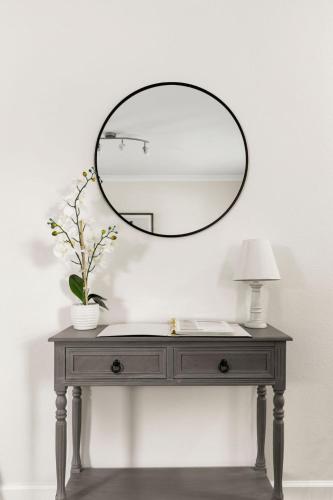 a vanity with a mirror on a table with a lamp at Private Heated Pool & Hot Tub, 4BR Gameroom in San Antonio