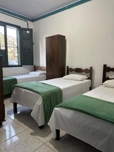 a room with three beds with green sheets at Pouso dos Viajantes Unidade Centro OuroPreto in Ouro Preto