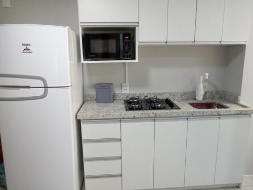 a kitchen with white cabinets and a white refrigerator at Apto Flor de Papoula in Canela