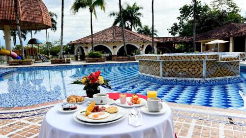 un tavolo con cibo accanto a una piscina di Tequendama Hotel Campestre Villavicencio a Villavicencio