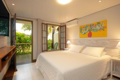 a bedroom with a white bed and a large window at Porto Pacuíba Hotel in Ilhabela