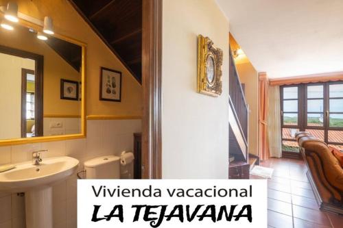 y baño con lavabo, aseo y espejo. en vivienda vacacional la tejavana, en Llames de Pría