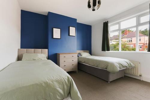 a bedroom with two beds and a blue wall at Semi-Detached House Featuring a Mezzanine Level in Nether Edge
