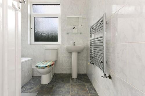 Baño blanco con aseo y lavamanos en Semi-Detached House Featuring a Mezzanine Level en Nether Edge