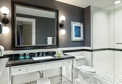 a bathroom with a sink and a toilet and a mirror at Le Meridien Dallas, The Stoneleigh in Dallas