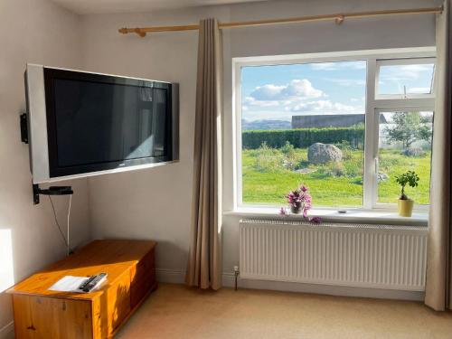 a living room with a flat screen tv and a window at Mountain Widok in Killorglin