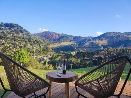a table with a glass of wine and two chairs at Pousada das Castanheiras in Monte Verde