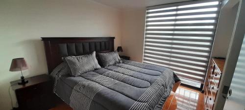 a bedroom with a bed and a large window at Cómodo departamento in Iquique