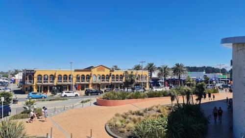 a large yellow building with palm trees and a street at Beachfront Haven in Christchurch