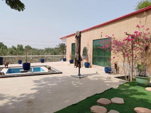 eine Terrasse mit einem Pool und einem Gebäude in der Unterkunft Princess Farmhouse in Al Ḩamīdīyah
