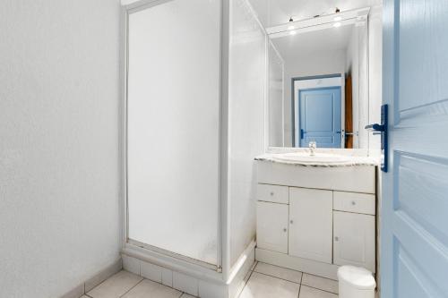 een witte badkamer met een wastafel en een spiegel bij Appartement Le Plan de La Tour in Plan-de-la-Tour