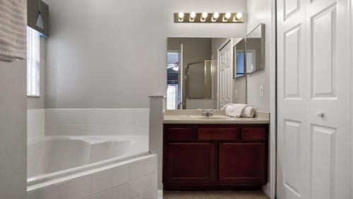 a bathroom with a tub and a sink and a mirror at Tranquil Formosa Gardens Villa in Orlando