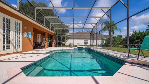 a swimming pool with blue chairs next to a house at Tranquil Formosa Gardens Villa in Orlando