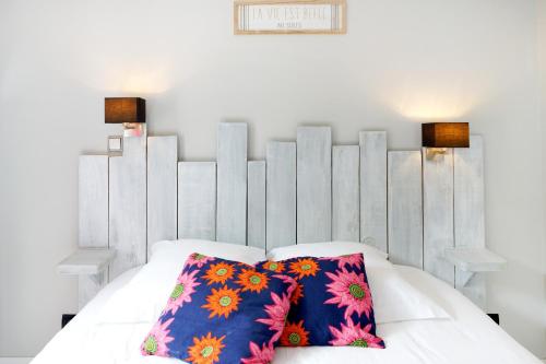 Una cama blanca con dos almohadas coloridas. en Appartement, 2 à 4 pers en Urrugne