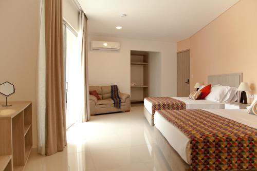 a hotel room with two beds and a chair at Hotel Santa Sofia in Puerto Salgar