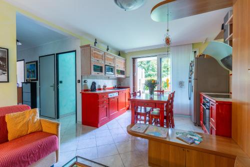 - une cuisine avec des placards rouges et une table dans une pièce dans l'établissement Maison Bruno, à Annecy