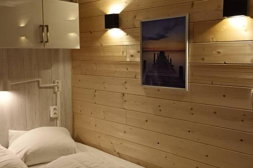 1 dormitorio con pared de madera, 1 cama y 1 foto en Ma maison sur L'eau - Lac du Der, en Giffaumont-Champaubert