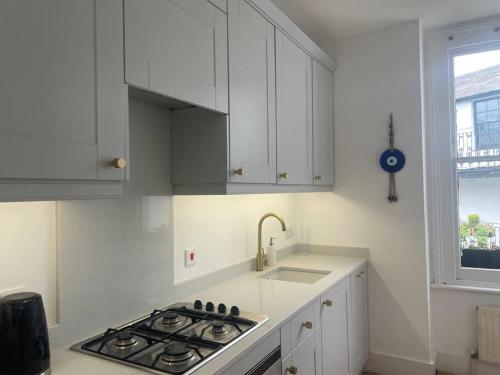 a white kitchen with a stove and a sink at Spacious 1-bedroom apartment in Belsize Village in London
