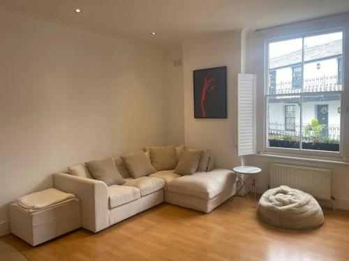 a living room with a couch and a window at Spacious 1-bedroom apartment in Belsize Village in London