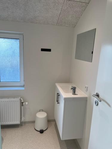 a white bathroom with a sink and a toilet at Hotel Kirkedal B&B in Lønstrup