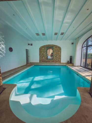 a swimming pool in a room with a blue ceiling at Gîte de l'Ourchet in Ramillies