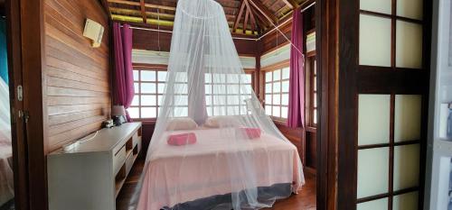 Schlafzimmer mit einem Bett mit Moskitonetz in der Unterkunft Heipoe Lodge in Uturoa