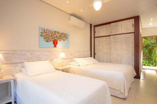 a bedroom with two beds and a tree painting on the wall at Porto Pacuíba Hotel in Ilhabela